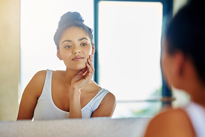 beautiful woman touches her face while looking in the mirror