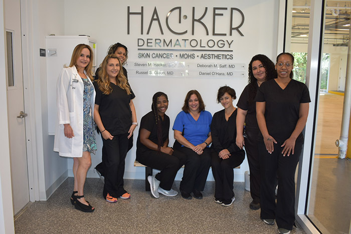 Hacker Dermatology staff poses with their office sign